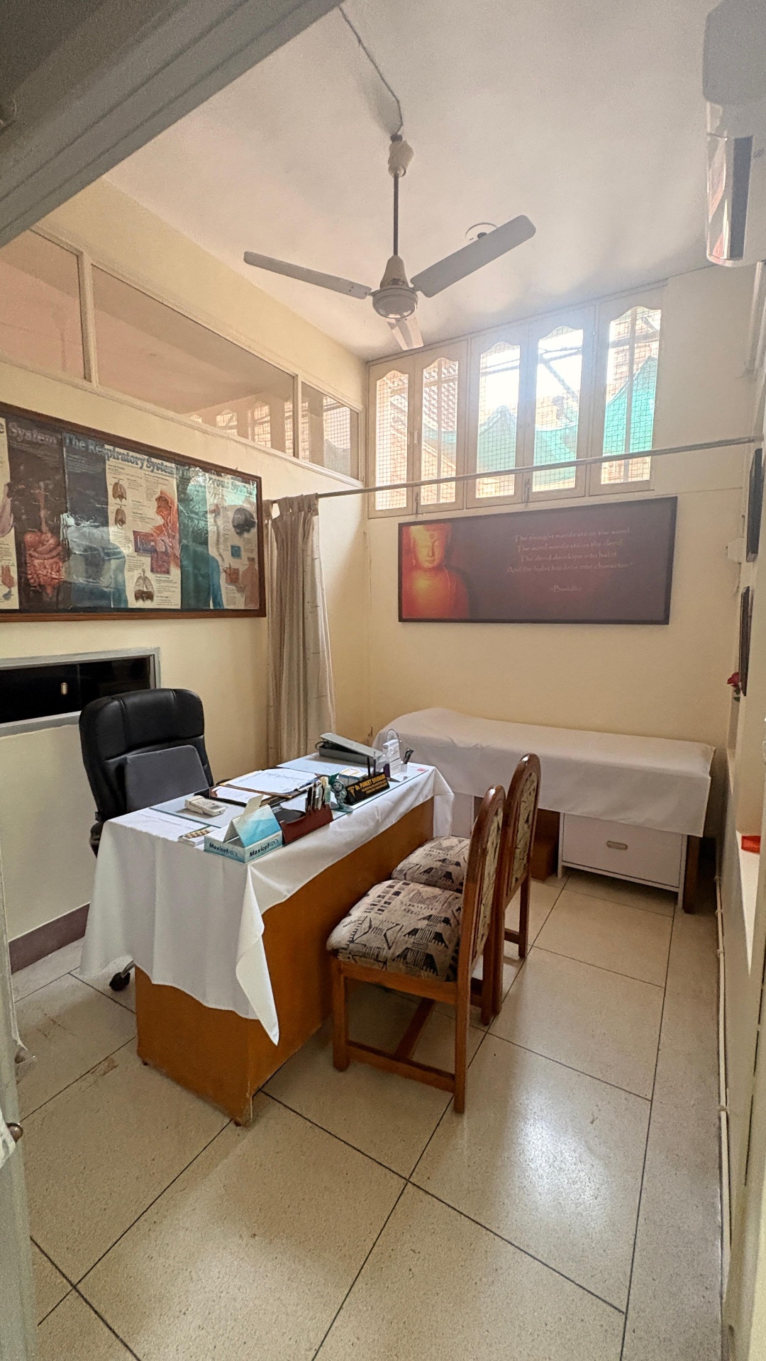 Consultation room with examination bed and Buddha quote