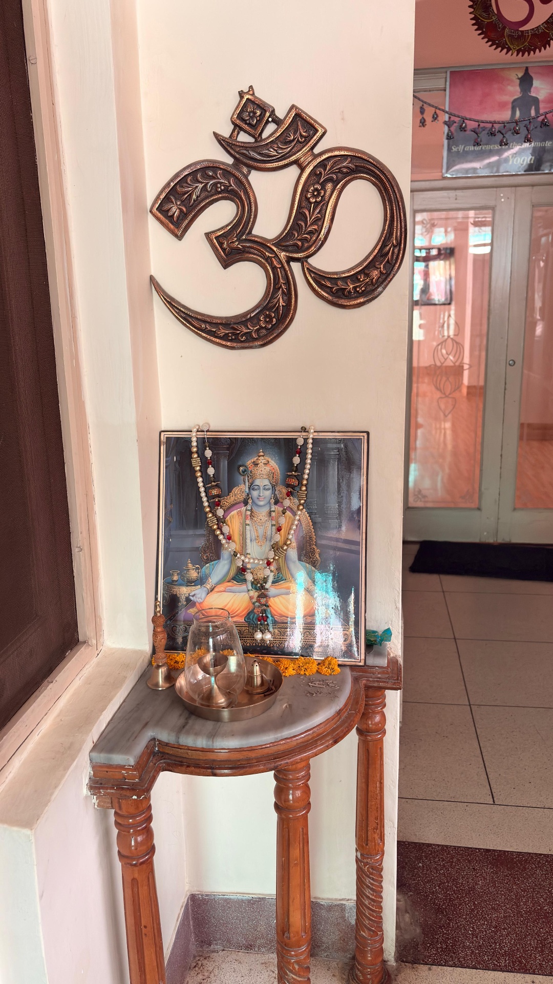 Copper Om medallion above a small shrine to Lord Patanjali